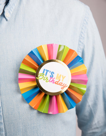 Colorful paper birthday badge with rainbow design from Cardmore, featuring festive glasses and wand accessories for celebration.