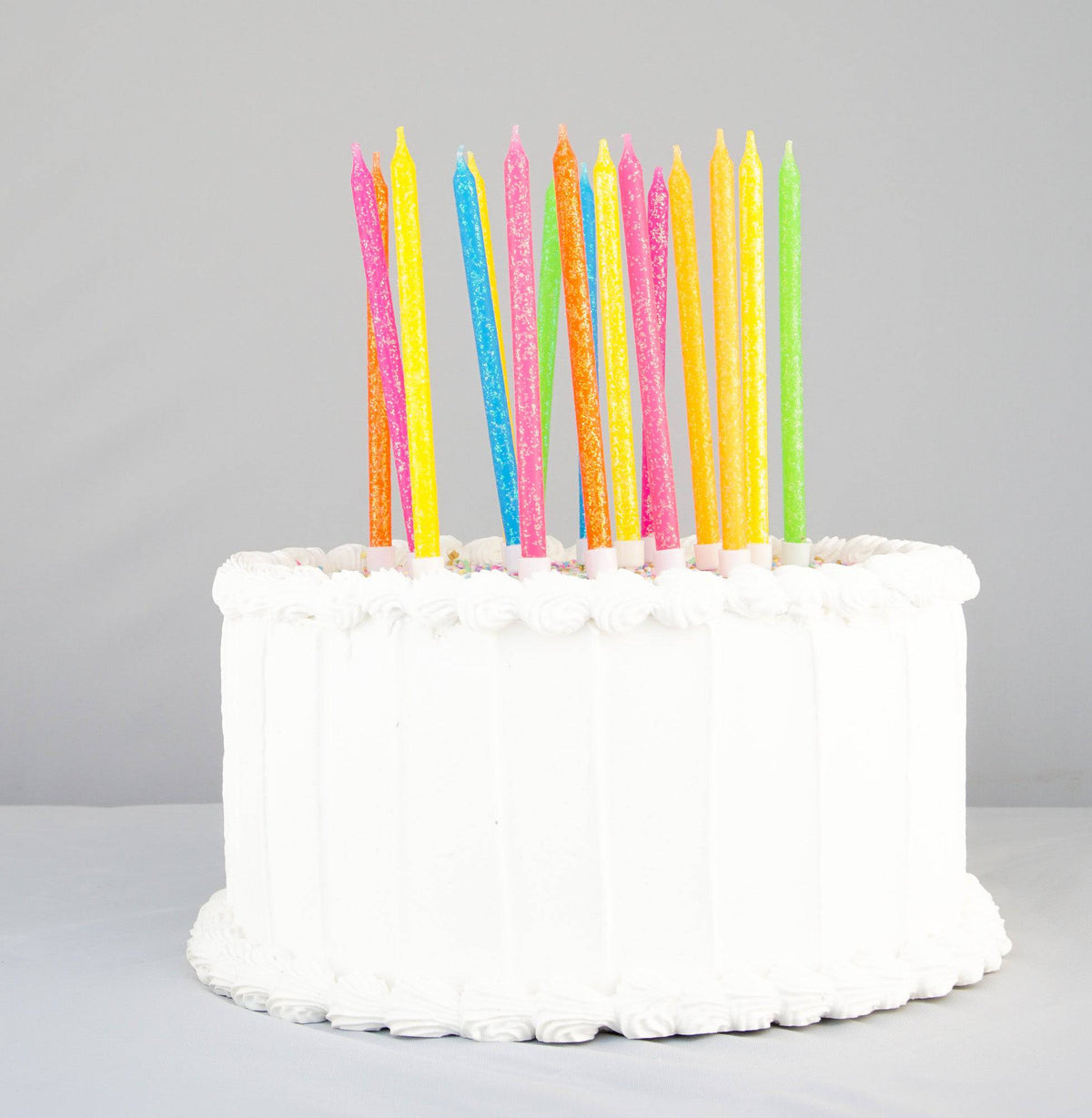 Tall neon rainbow candles from Party Partners candle set, featuring vibrant colors and sleek design on a white background.